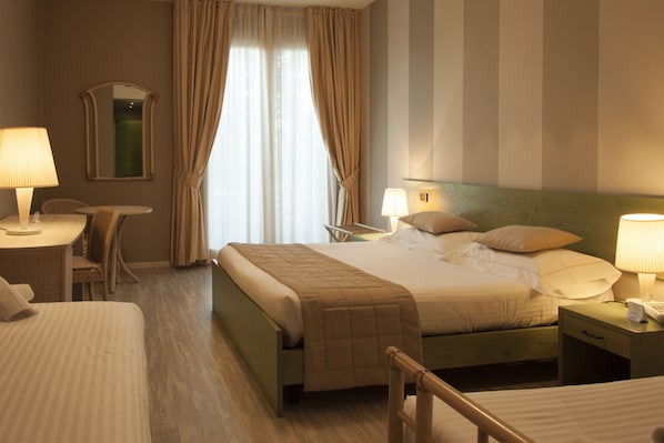 A hotel room with a large bed, bedside tables with lamps, a chair, a desk, and a mirror. - Hotel Berta (Desenzano del Garda)