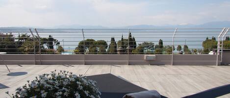 Una terraza con piscina, una tumbona y vistas al mar y a las montañas.