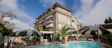 A hotel named "hotel BERTA" with a swimming pool, outdoor seating, and umbrellas.