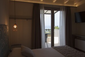 A hotel room with a bed, a TV mounted on the wall, and a view of the outdoors through a sliding door. - Hotel Berta (Desenzano del Garda)