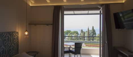 Une chambre d’hôtel avec un lit, une télévision et un balcon équipé d’une table et de chaises.