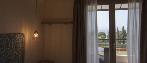A hotel room with a bed, a desk, and a view of the outdoors through a balcony.