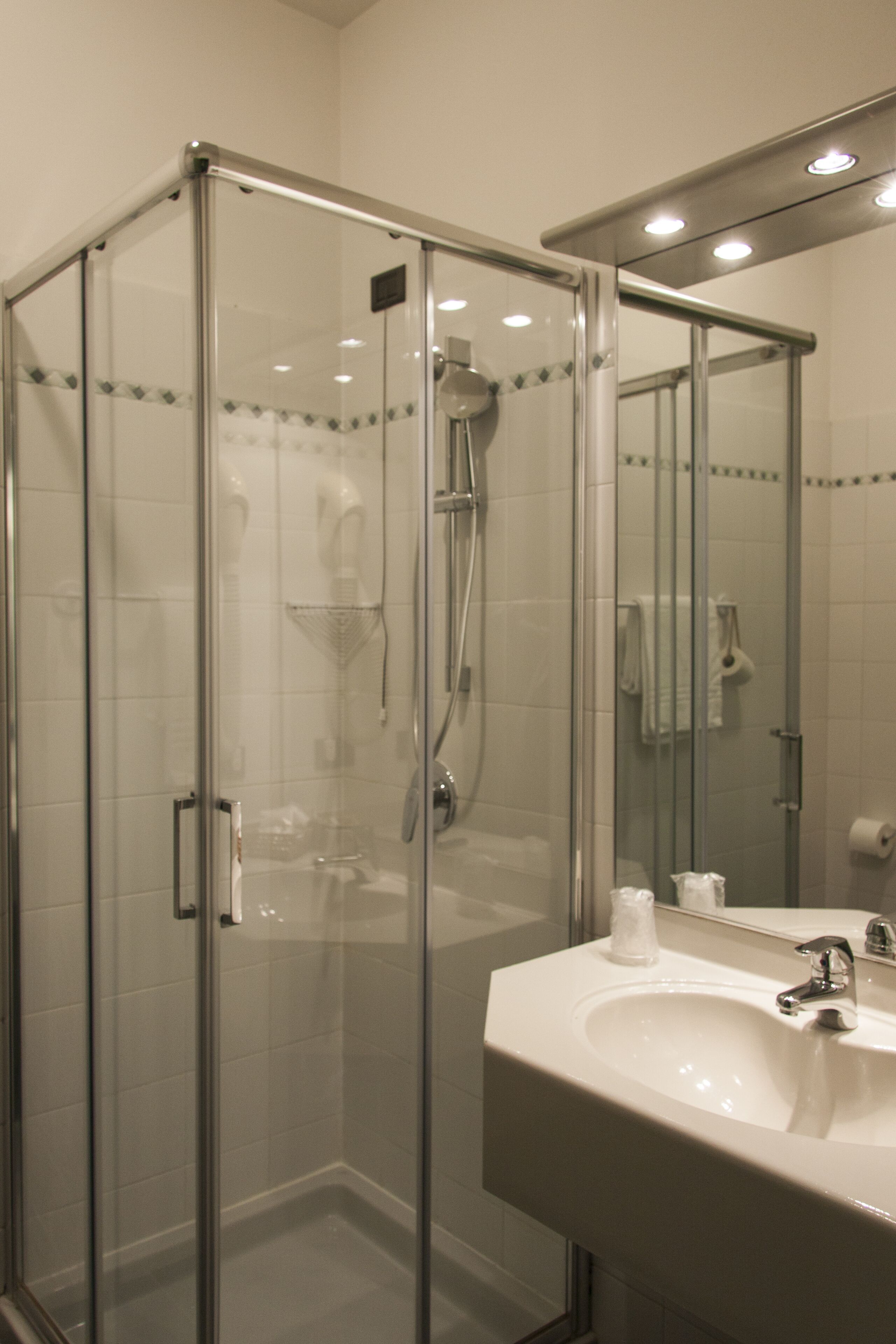 Ein modernes Badezimmer mit einer einachigen Duschkabine, einem weißen Waschbecken und einem Spiegel darüber.