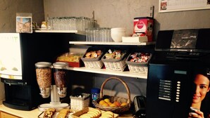 Una encimera de cocina con una cafetera, una licuadora y diversos alimentos como pan y frutas.