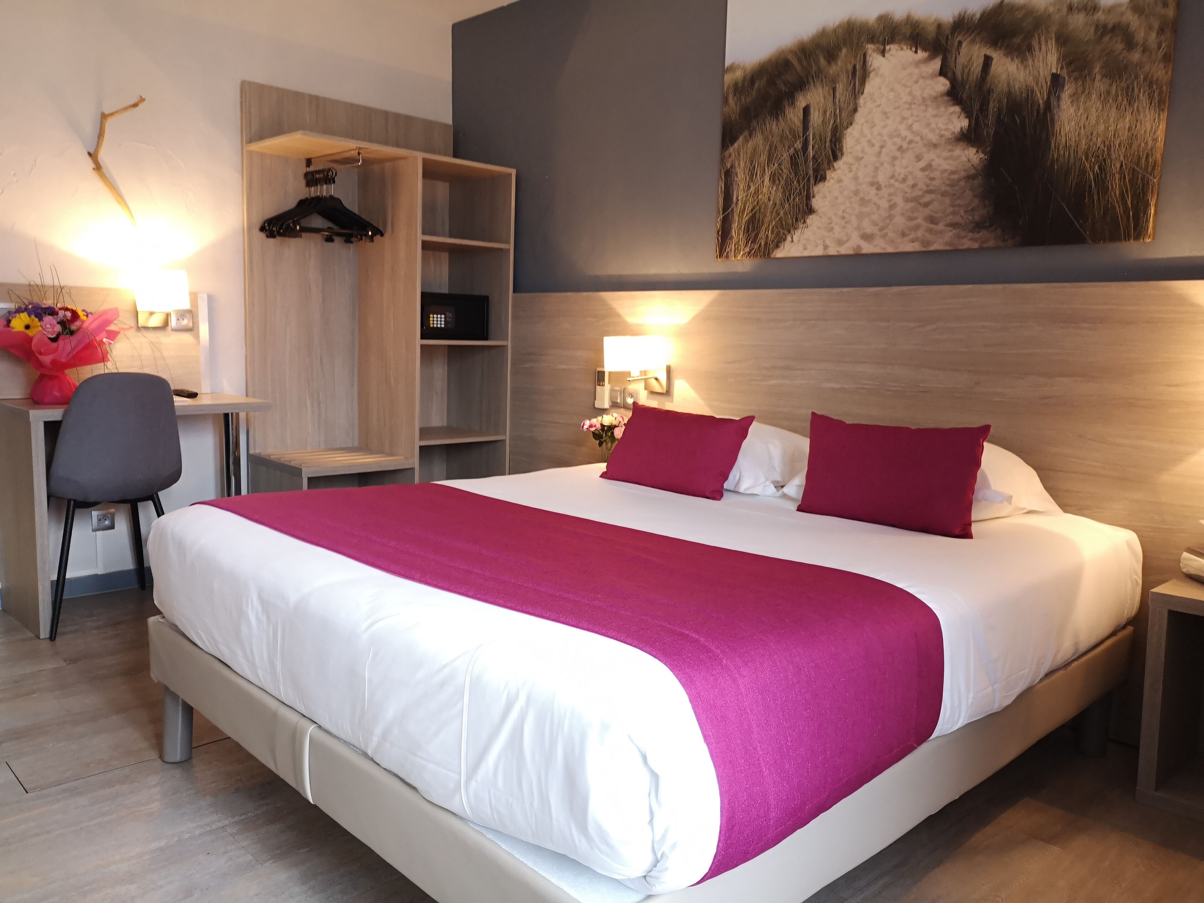 Ein Hotelzimmer mit einem großen Bett, einem Schreibtisch, einem Stuhl und einem Kleiderschrank.