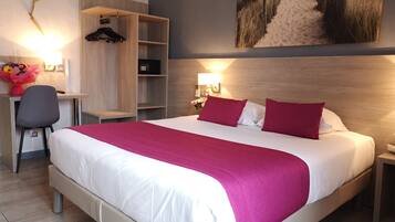 Une chambre d’hôtel avec un grand lit, un bureau, une chaise et une armoire.