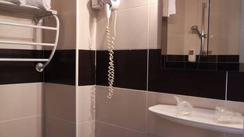 A modern bathroom with a white sink, a mirror, a towel rack, a hairdryer, and a shower.