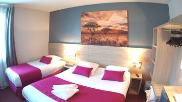 A hotel room with two beds, a painting of a sunset, a wooden headboard, and a nightstand with a lamp.