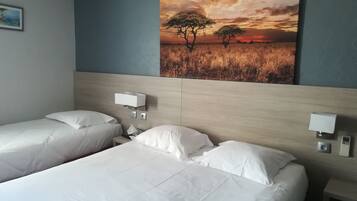 A hotel room with two beds, a headboard, bedside tables, and a painting of a sunset.