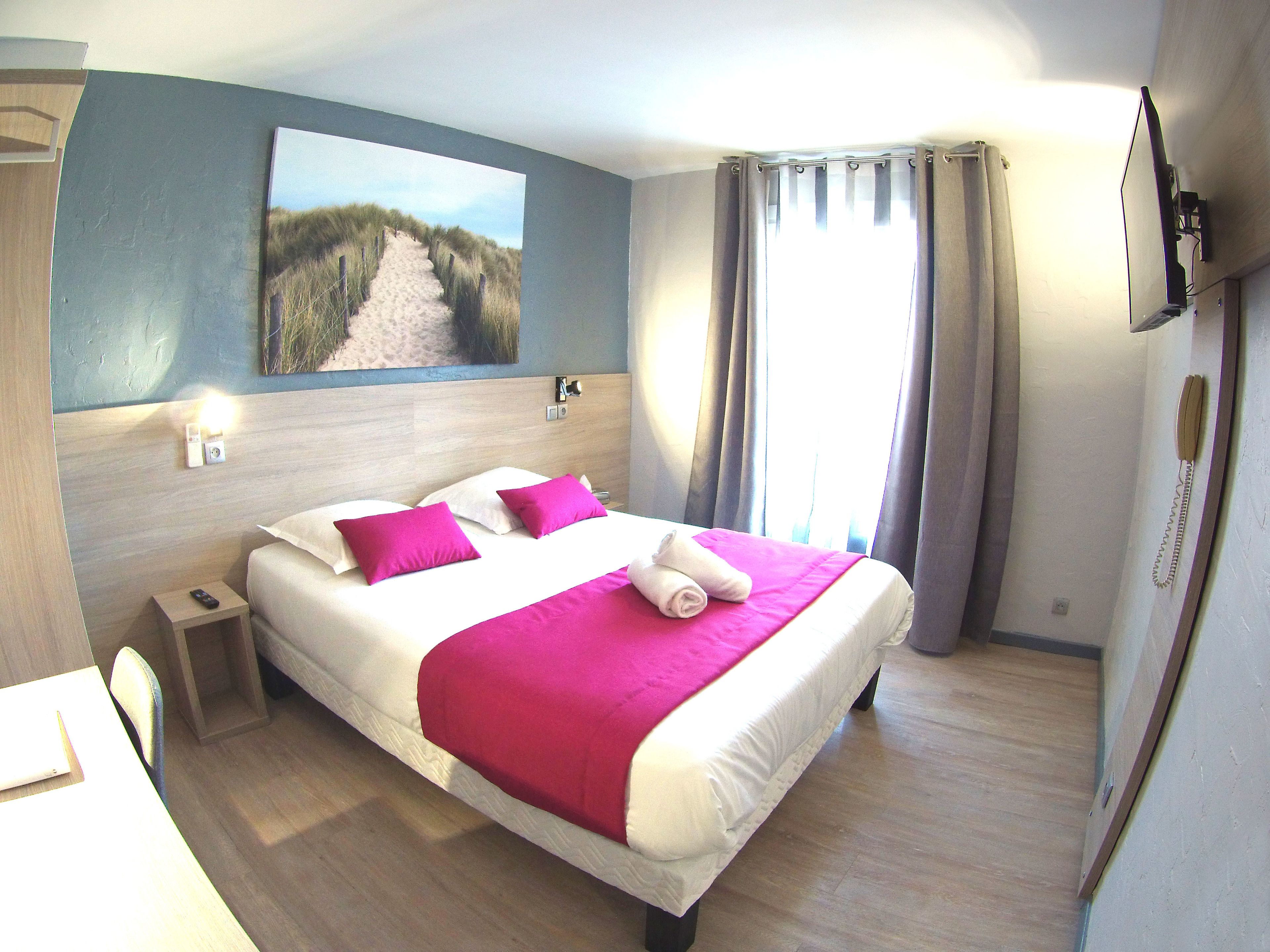 A hotel room with a bed, a nightstand, a telephone, and a painting on the wall.
