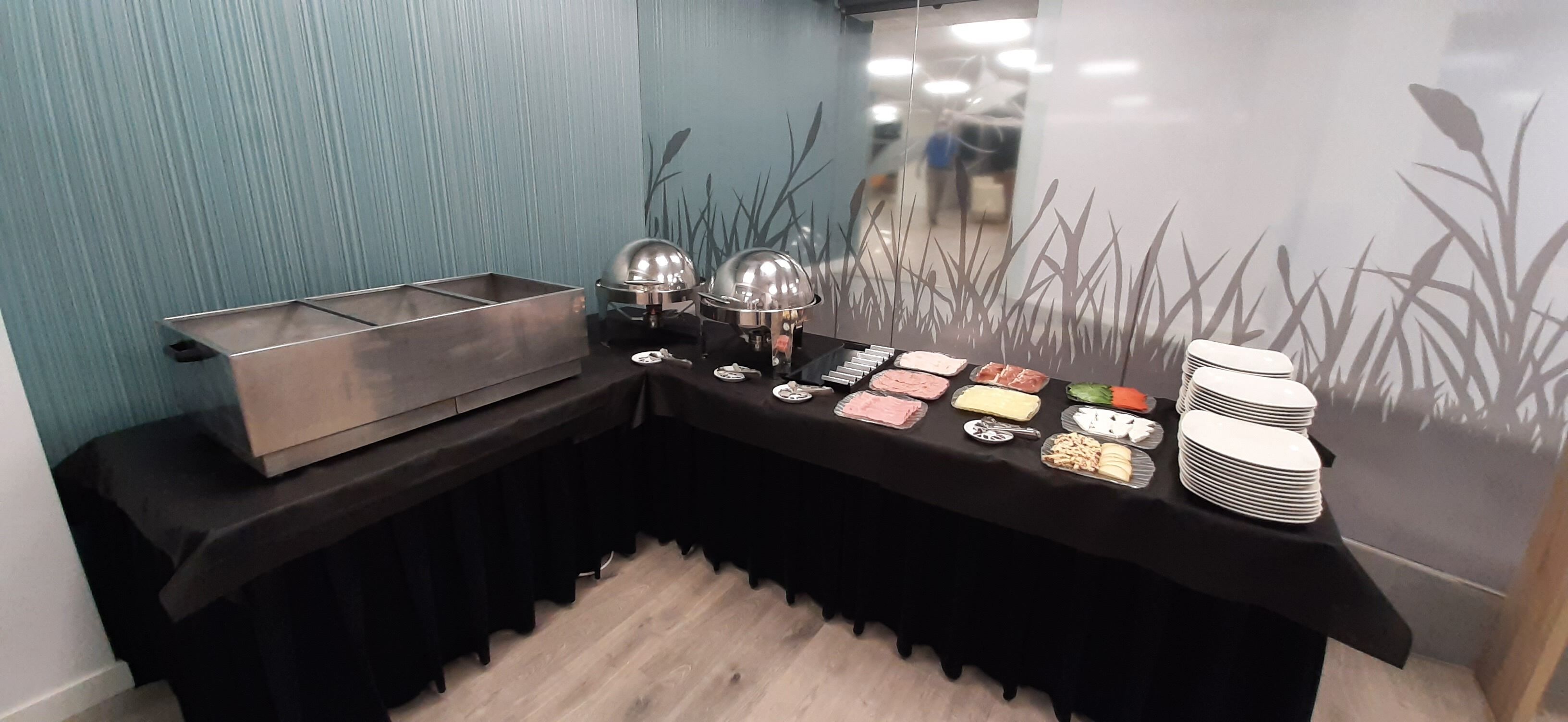 Montaje de bufé con diversos alimentos y utensilios de servicio.