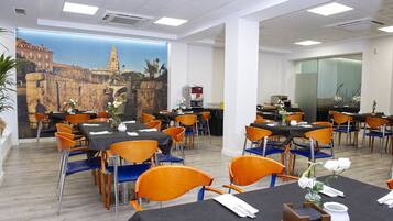A dining area with tables and chairs, a mural of a cityscape, and a coffee machine.