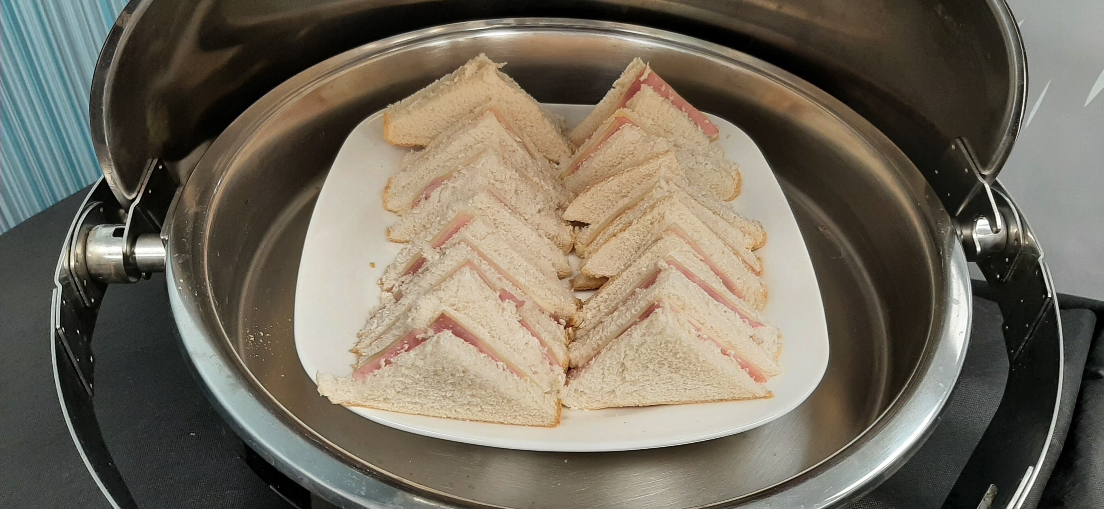 A stainless steel pot containing sliced sandwiches on a white plate.