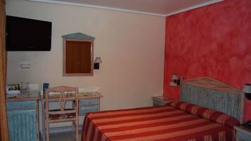 Un dormitorio con cama, un escritorio con silla, televisor y armario.
