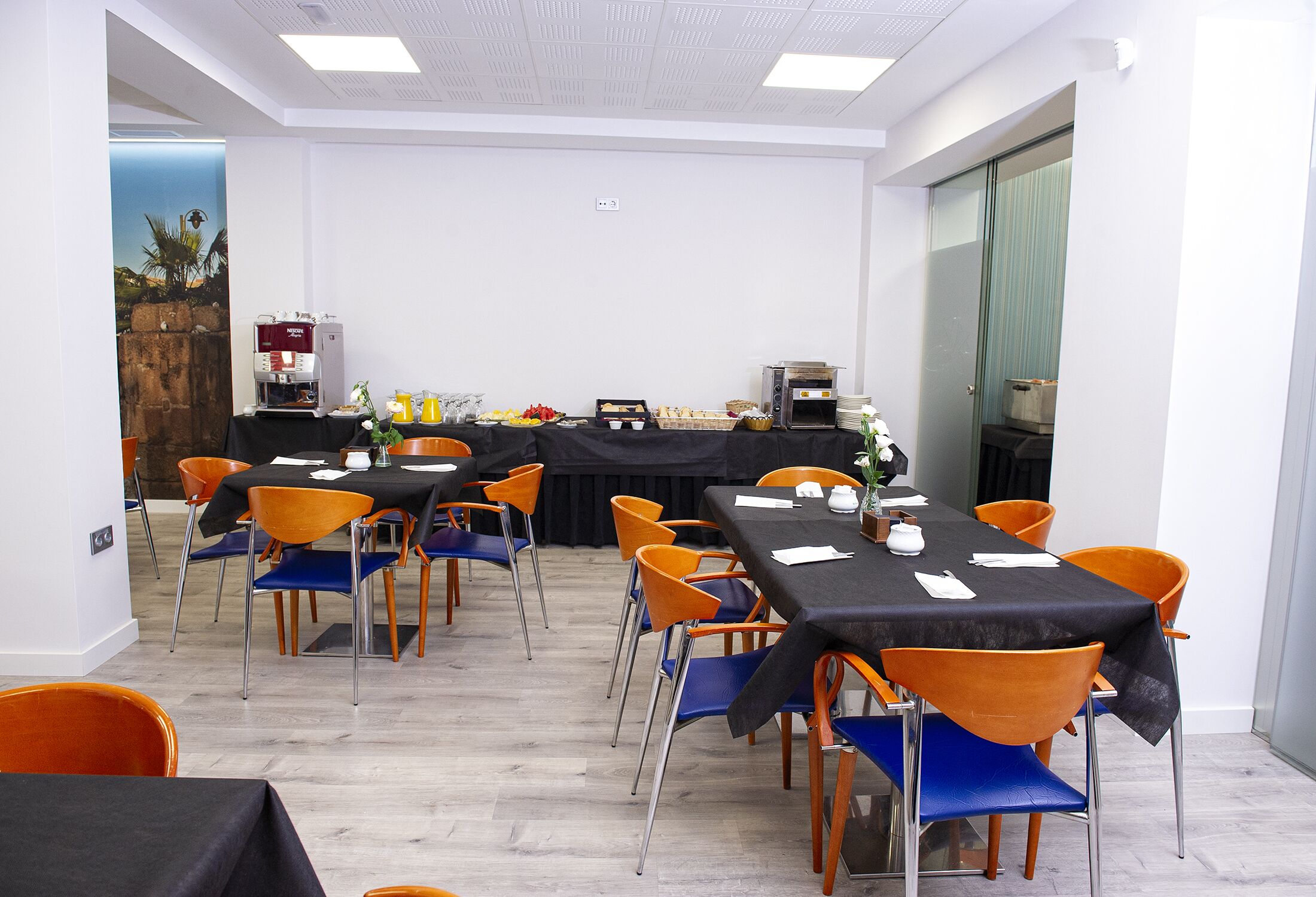 A conference room with multiple tables and chairs, equipped with a coffee machine and a toaster oven.