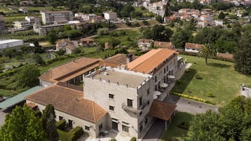 Un edificio grande de varios pisos con un patio interior, rodeado de vegetación y edificios residenciales.
