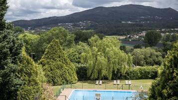 Una piscina rodeada de árboles, con vista a una colina y edificios a la distancia.