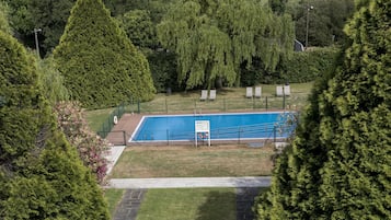 Vista aerea di una piscina circondata da alberi e da un'area verde con lettini.