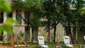 A swimming pool with two white lounge chairs and a stone building in the background.