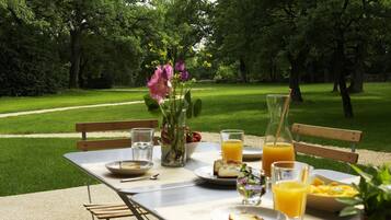 A picnic table set up in a park with a view of a grassy area and trees.