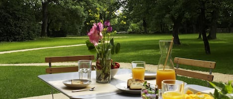 A picnic table set up in a park with a view of a grassy area and trees.