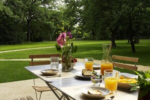 Enjoy a meal in a serene park-like setting with a beautifully set table and lush green surroundings.