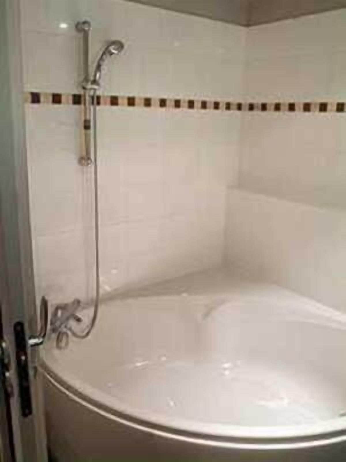 A bathroom with a bathtub, a shower, and a tiled wall.