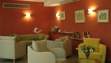 Una sala de estar con sofás color beige, un sillón amarillo y una mesa de centro con flores.