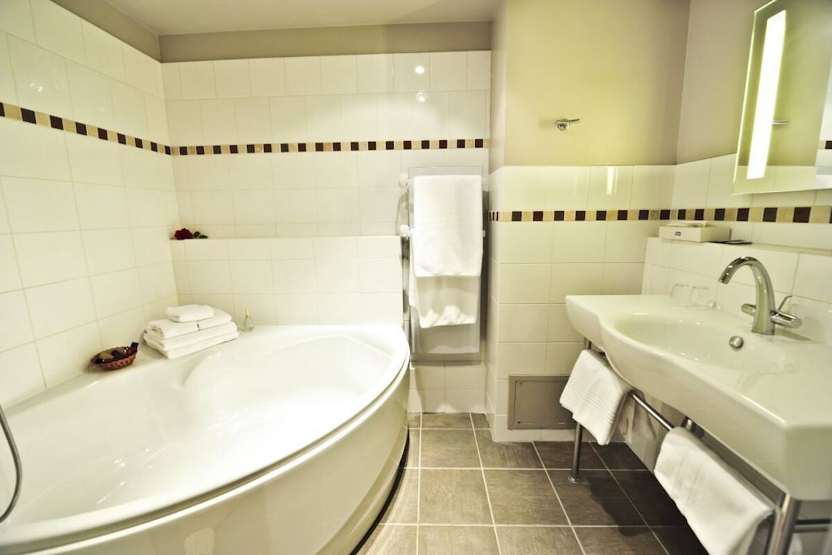 A modern bathroom with a large bathtub, a sink, and a shower.