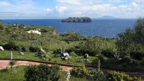 A coastal landscape with a small island, lush greenery, and a clear sky. - Calabattaglia (Ventotene)