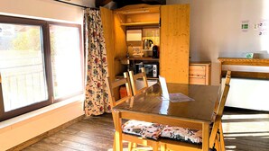 A compact room with a wooden dining table and chairs, a small kitchenette, and a window with curtains. - Villa ai Tigli Venice Airport Rooms Online Check-in & Keypad Access (Mestre)