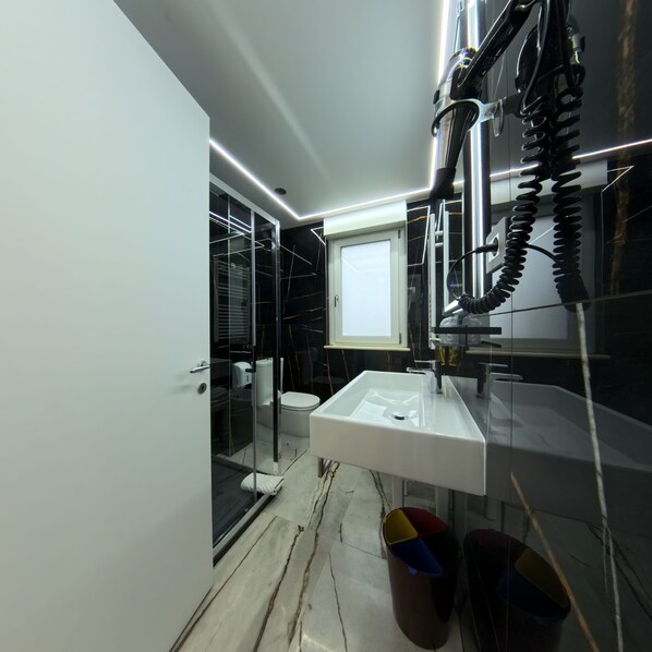 Un baño moderno con un lavabo blanco, cabina de ducha con mampara de vidrio y un inodoro.