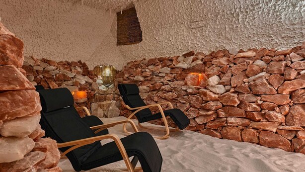 Un cuarto de spa con paredes de piedra, dos sillones negros y una chimenea de piedra.