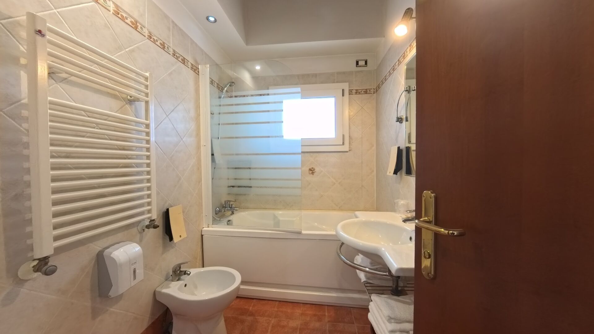 Une salle de bain avec une baignoire, deux lavabos, un bidet et un porte-serviettes.
