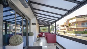 Un moderno vestíbulo de hotel con fachada de vidrio, asientos rojos y vista a la calle.