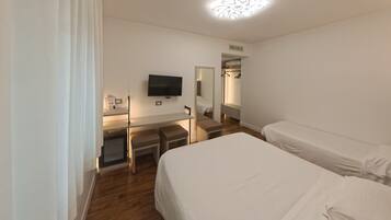 Una habitación de hotel con cama, escritorio, televisión y armario.