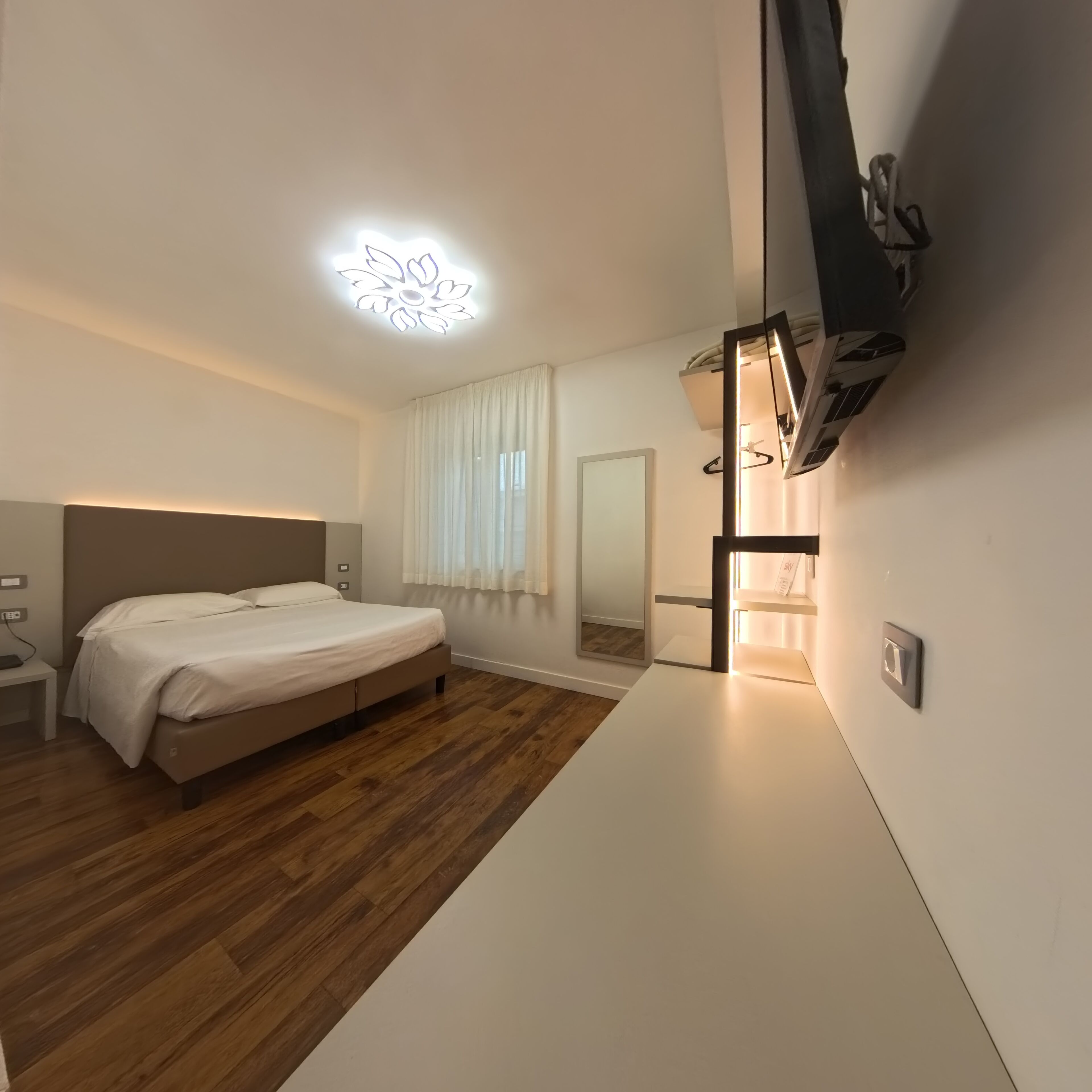 Une chambre moderne avec un lit, une table de chevet et un luminaire fixé au mur.