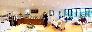 Een ruime kamer met een grote eethoek, een keuken en uitzicht door de ramen.