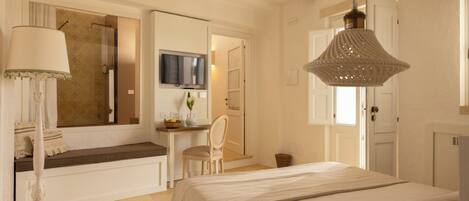 Un dormitorio con cama, escritorio, silla, lámpara y televisión.