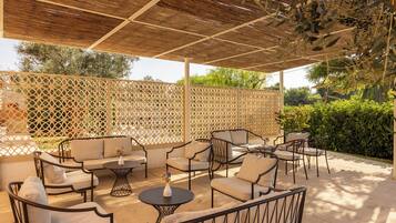 Eine Außenpatio mit einer Holz-Pergola, gepolsterten Sitzmöbeln und einer dekorativen Vase.
