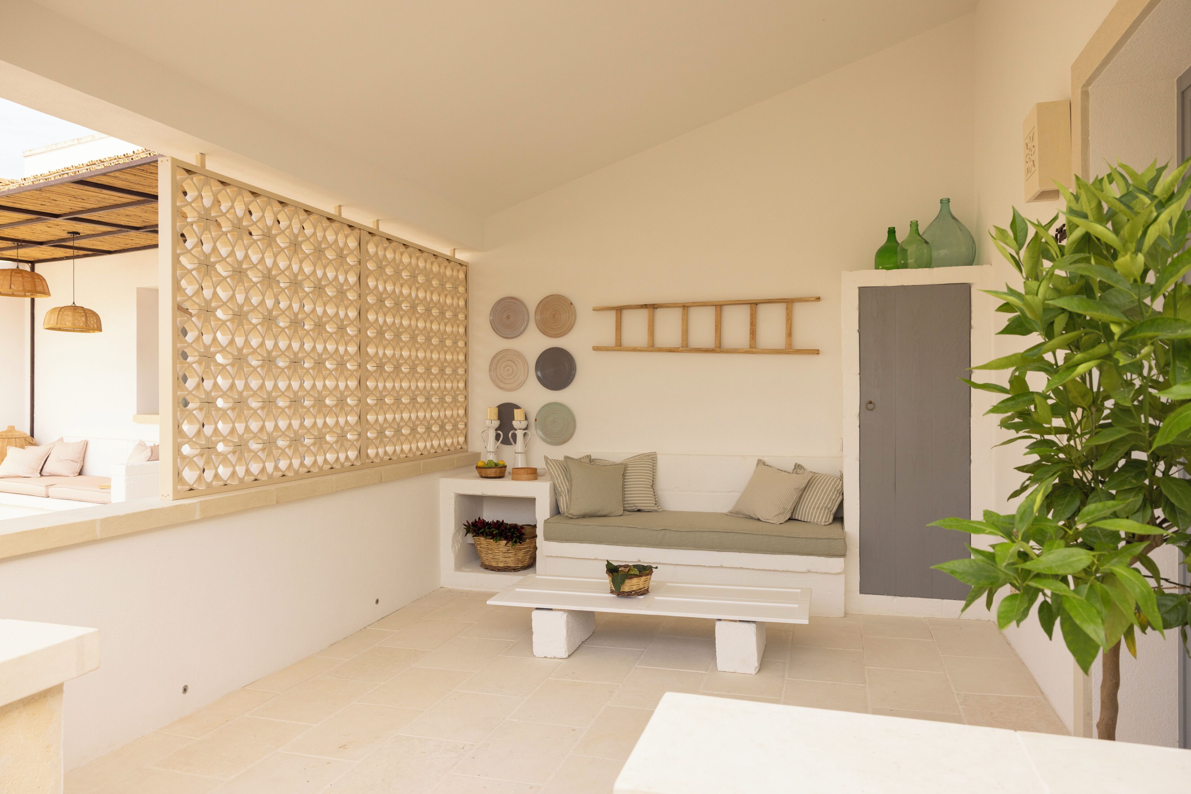 A modern living room with a white sofa, a wooden bench, a decorative wall panel, and a potted plant.