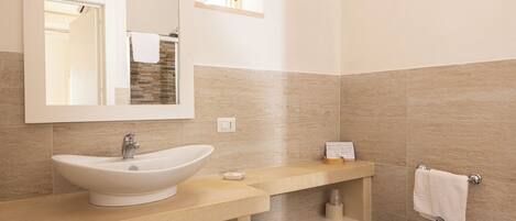 Un baño moderno con un lavabo de pedestal grande, un bidé y un espejo sobre el lavabo.