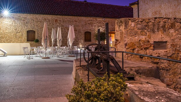An outdoor seating area with stone walls and a fountain, featuring tables and chairs. - Hospedium Hotel Casino del Tormes (Salamanca)