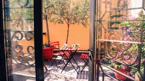 Un balcon avec une table et des chaises, un pot de fleurs et une vue sur un arbre et des fleurs.
