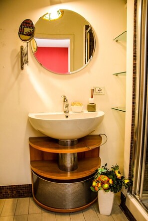 A bathroom with a round mirror, a white sink, and a shower area. - Aldebaran Bed and Breakfast (Rome)