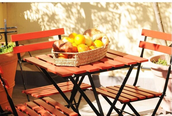 A picnic setup with a basket of fruits and bread on a wooden table and benches.