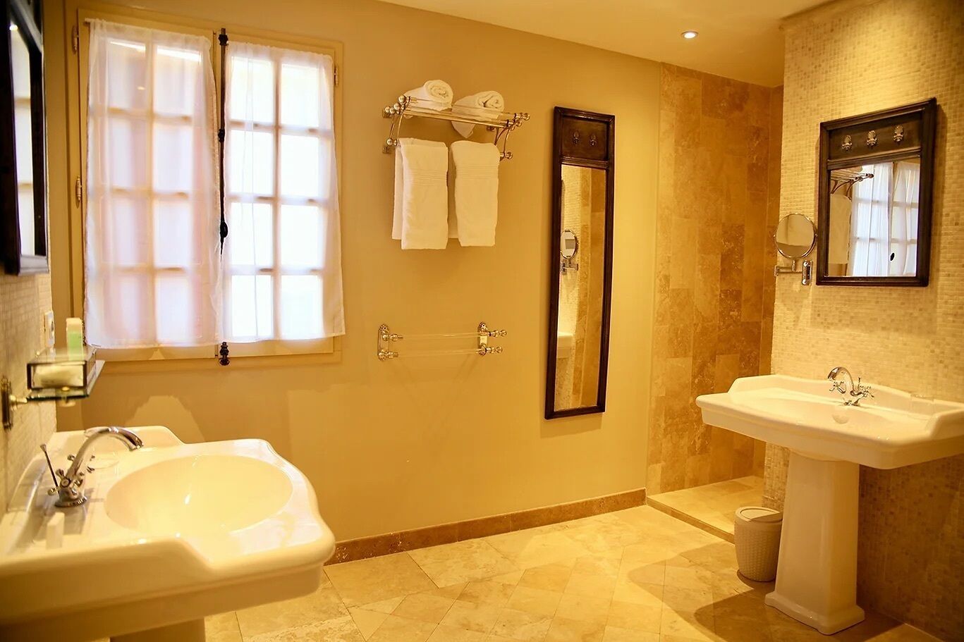 A bathroom with two sinks, a large mirror, and a towel rack with towels.