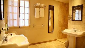 A bathroom with two sinks, a large mirror, and a towel rack with towels.