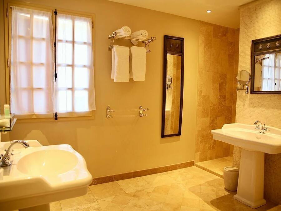 A bathroom with two sinks, a large mirror, and a towel rack with towels.