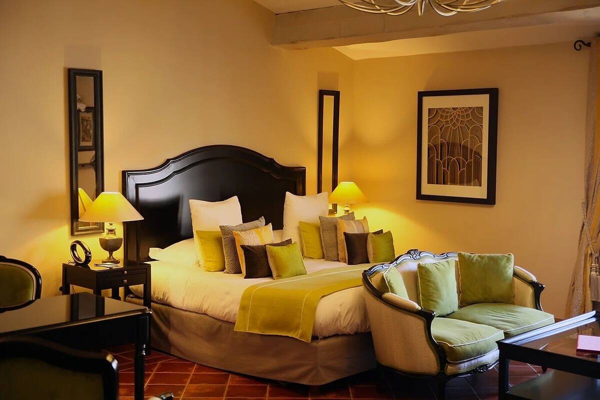 Een hotelkamer met een groot bed, twee bedlampen, een stoel, een bureau en een lijst aan de muur.